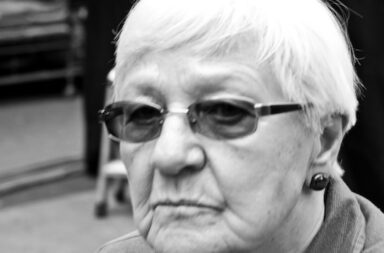 Ältere Frau mit kurzen Haaren schaut in Kamera