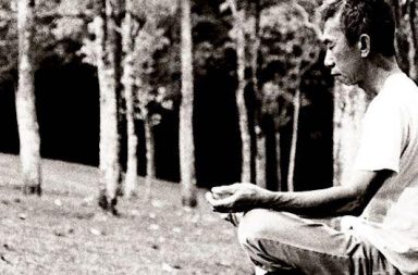 Asiate im Yogasitz im Wald schwarz weiß