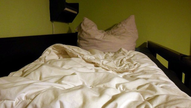 Bett mit Kissen vor einer grünen Wand