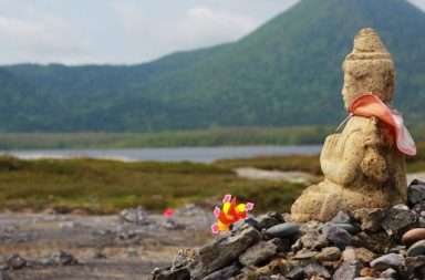 Buddha auf Steinberg vor Landschaft