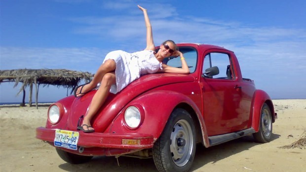 Frau auf rotem VW Käfer