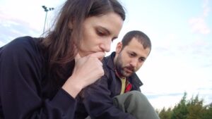 Frau und Mann sitzen im Park und überlegen