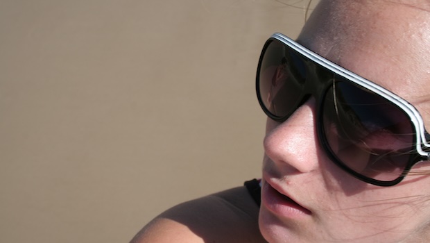 Frau mit Sonnenbrille vor graubraunem Hintergrund