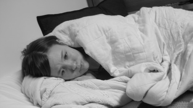 Frau liegt traurig im Bett mit Decke