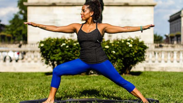 Frau macht Yoga auf einer Wiese in der Kriegerpose