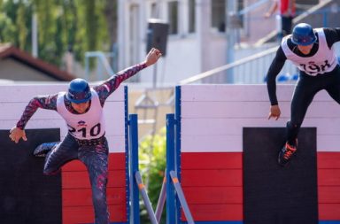 Zwei Männer mit Helm und Sportdress beim Hindernislauf