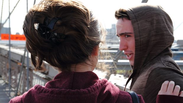 Junge mit Kapuze und Mädchen auf Brücke mit Wind