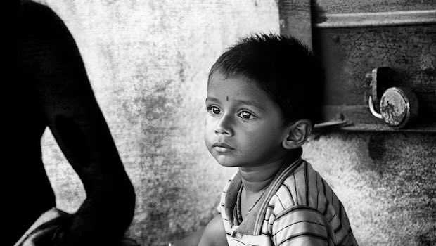 Kind in armer Umgebung schaut in die Ferne, Mann daneben