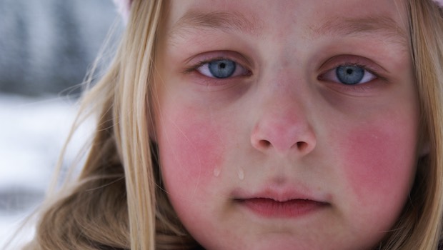 Gesicht eines blonden Kindes mit blauen Augen, Schnee im Hintergrund