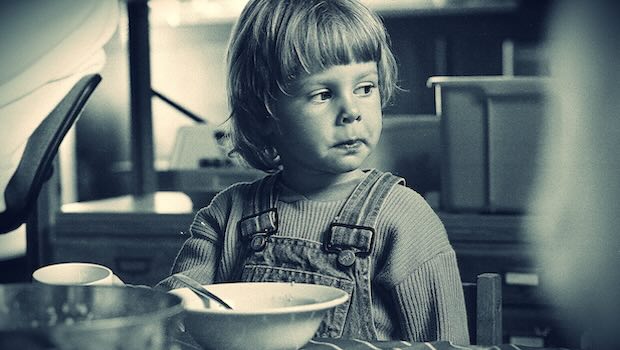 Kind sitzt am Tisch mit Schüssel