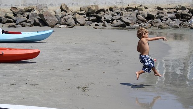 kleiner Junge, werfend am Strand