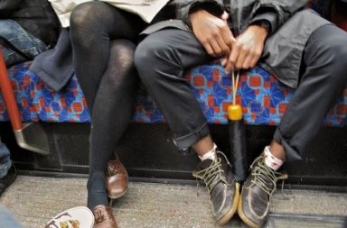 Mann sitzt breitbeinig in Bahn, Frau sitzt eng verknotet