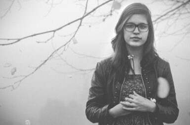 Mädchen mit Brille und Lederjacke im Nebel