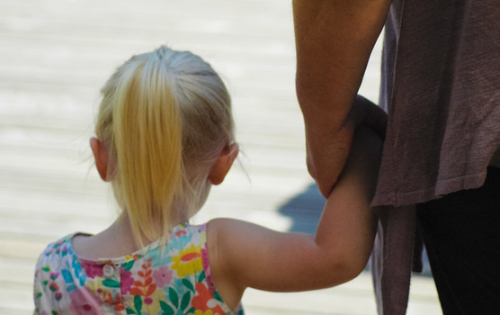 Ein kleines Mädchen an der Hand eines Erwachsenen