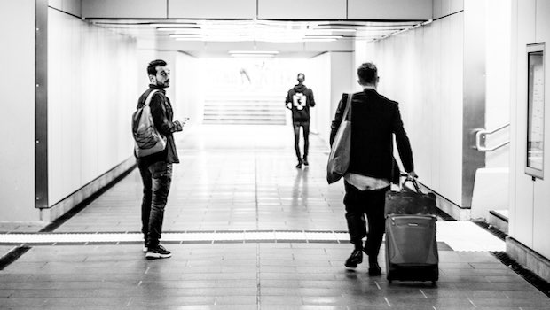 Mann mit einem Rollkoffer in einem Bahnhof und ein anderer Mann, der zurückblickt