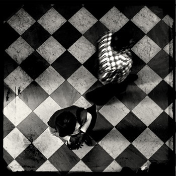 Mensch und leuchtende Figur auf schwarzweißen Kacheln, von oben.