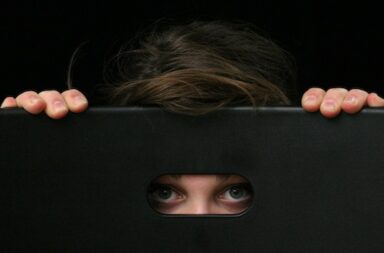 Mensch versteckt sich hinter schwarzer Box