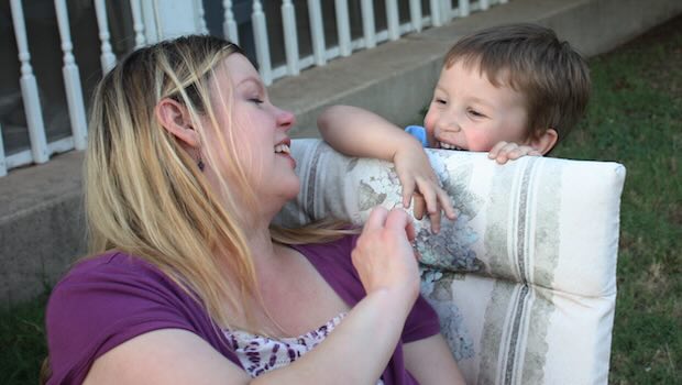 Mutter sitzt im Garten und macht Spaß mit dem Kind