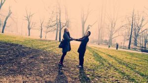 Paar hält sich an den Händen im Park bei Gegenlicht der Sonne