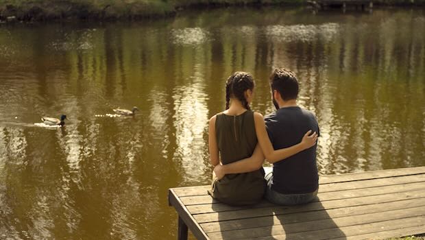 Paar sitzt auf Steg am Wasser