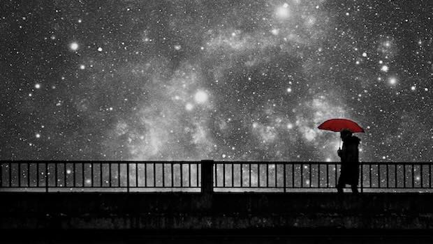 Person mit Schirm auf Brücke unter Sternenhimmel