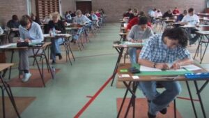 Schüler sitzen an Einzeltischen und schreiben ein Examen