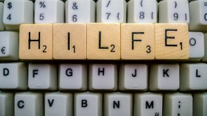 Das Wort Hilfe mit Scrabble-Buchstaben auf einer Tastatur gelegt