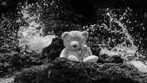 Teddy auf Fels am Meer Wellenspritzer