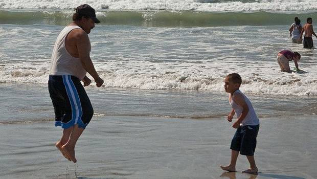 Spingender Vater mit Sohn am Strand