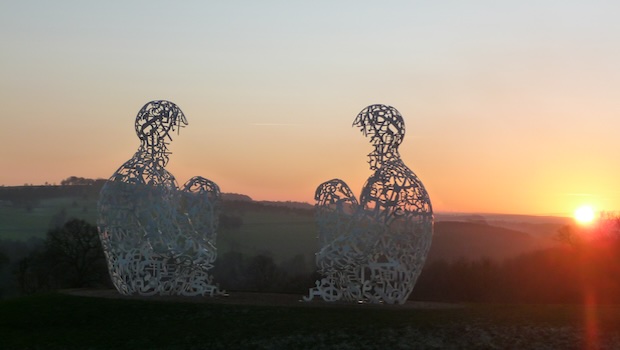Zwei Drahtfiguren sitzen vor Sonnenuntergang
