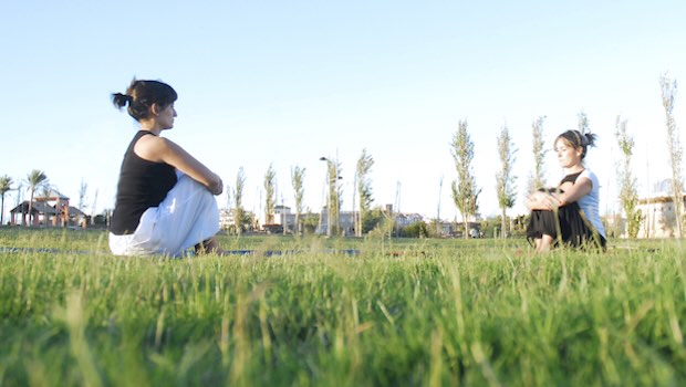 Zwei Frauen auf einer Wiese machen Yoga