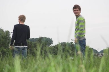 Zwei junge Männer stehen auf einer Wiese.